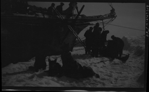 Image of Five men at sledge by prow; dogs resting in foreground